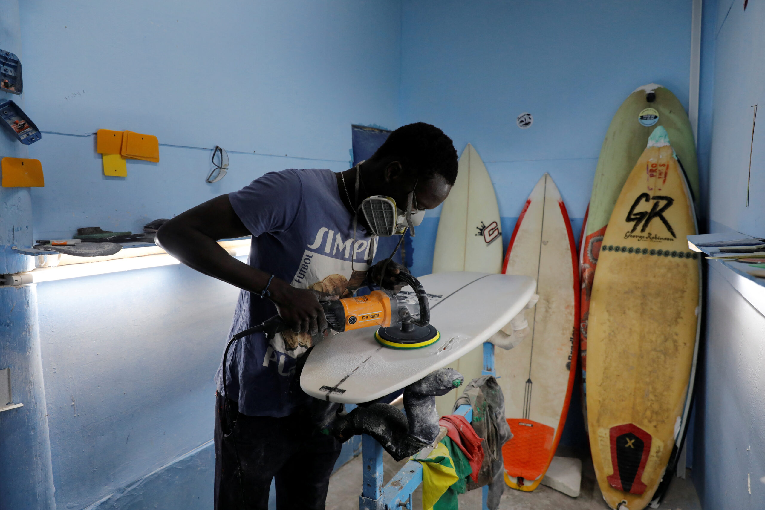 Pape Diouf, 27, repairs a damaged surfboard in his workshop named Sunugal surfboard repair in Yoff beach, Dakar, Senegal. REUTERS/Ngouda Dione